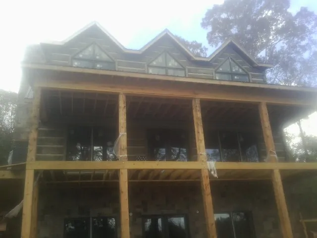 Dormers and porch framing on a large log home under construction — Roof Coating work by our crew in West Lebanon