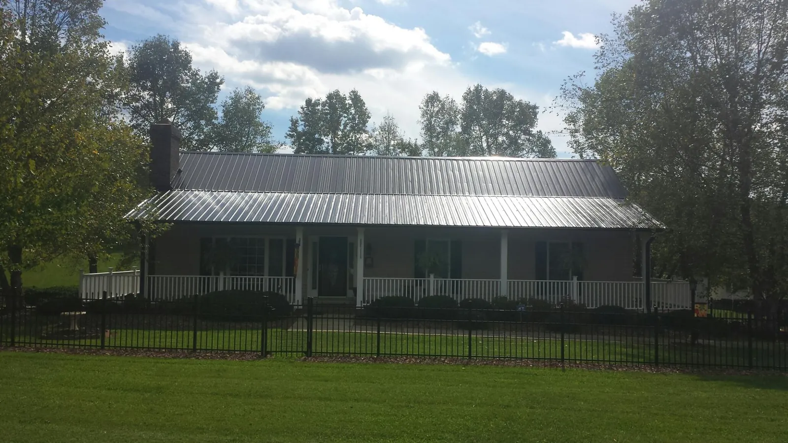 Gray metal roof on a brick ranch with a full width front porch — Gutter Guard Installation work by our crew in West Lebanon