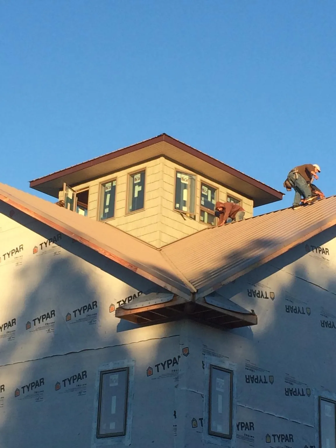 Roofers working around a rooftop cupola on a new metal roof at sunset — Roof Waterproofing in West Lebanon by Roofing Brothers